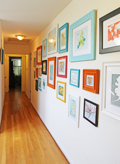 Hallway gallery with colorful frames on a white wall.