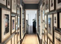 Hallway gallery with dark walls covered in many picture frames.