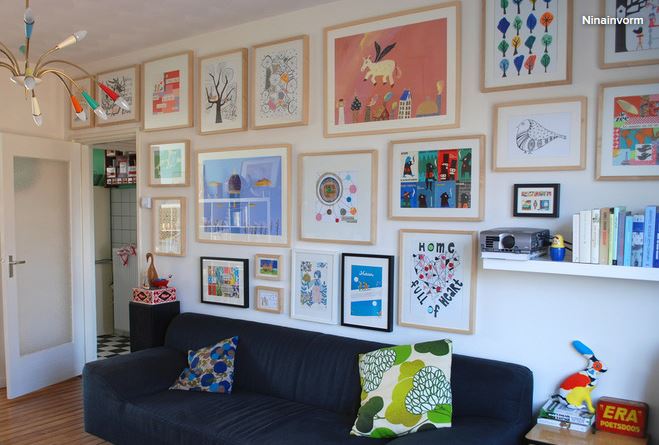 Living room gallery with a bright wall covered in framed art pieces.