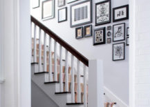 A white-themed stairway gallery with black framed pictures.