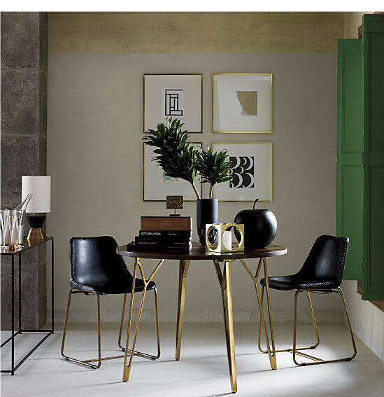 A sleek black and gold dining table is the centerpiece of the image. Two matching chairs are pulled up to the table.