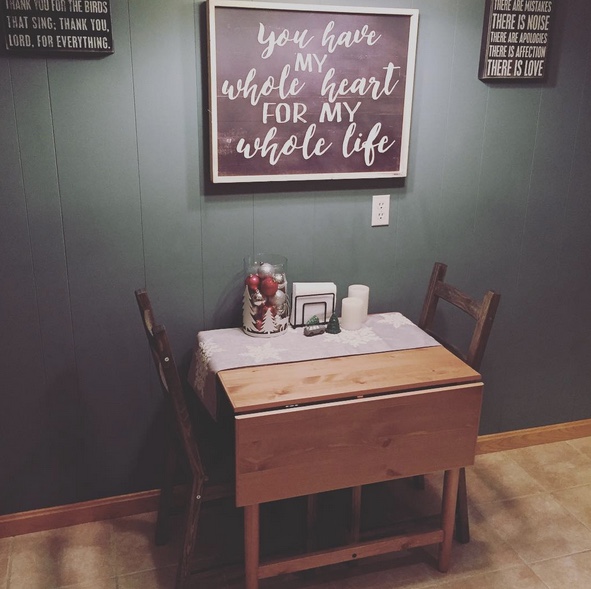 A cozy setup with a small table and two chairs is captured in the image. A sign that reads 'you love my whole life' is placed on the table, adding a romantic touch to the scene.
