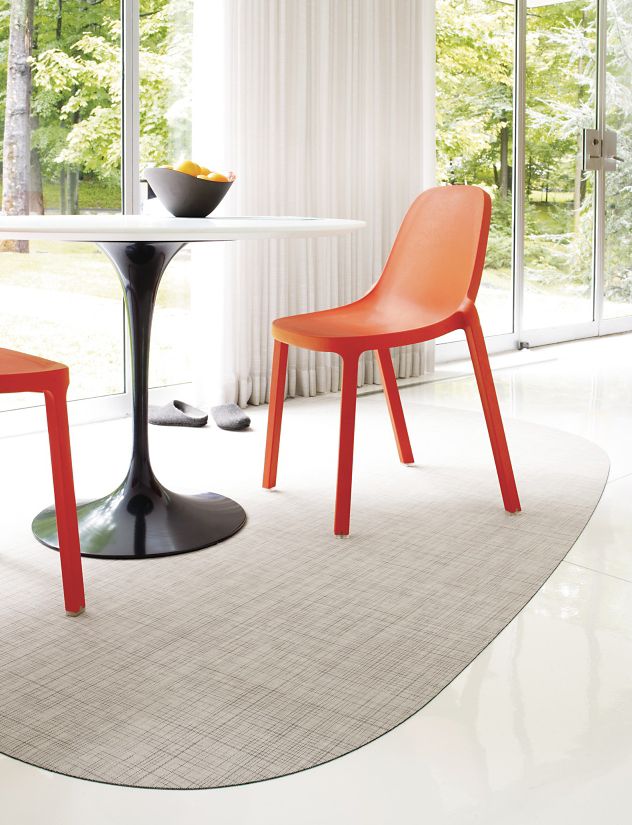 A minimalist white table is surrounded by two vibrant red chairs. The chairs' curved backs and sleek legs add a touch of modernity to the scene.