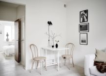 A minimalist white room with a wooden table and two chairs.