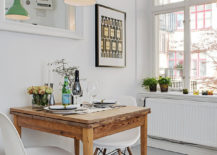 A bright white small dining room with a wooden table and two white chairs.