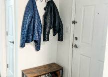 Entryway with a small bench that doubles as shoe storage with coat hung above it.