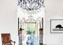 Entryway with a chandelier and a round hardwood table flanked by a chair.