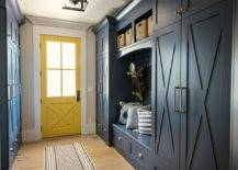 An entryway with blue cabinets and a yellow front door.