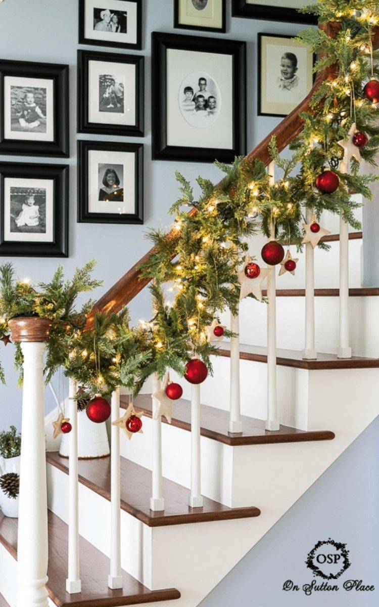 christmas garland and ornaments on banister with black photo frames in background