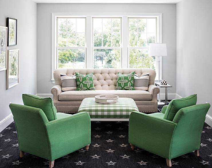 Charming beige and green living room is furnished with a beige tufted sofa topped with green pillows and placed on a black star pattern rug beneath a window. The sofa faces a green gingham ottoman seating two green accent chairs.