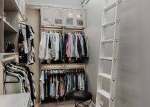 Walk in closet features a white ladder on rails and gray shelves under a tall ceiling