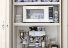 Coffee bar hidden in cupboard with microwave and coffee machine.