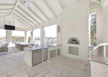 Spacious covered patio features a white brick outdoor kitchen with custom pizza oven.