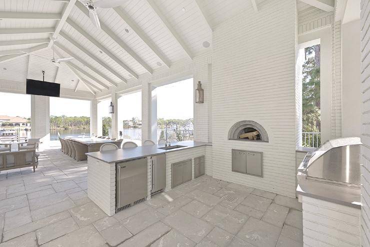 Spacious covered patio features a white brick outdoor kitchen with custom pizza oven.