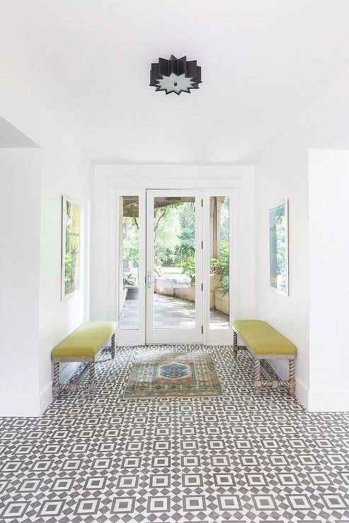 Entryway features citron fabric on gray spindle benches over white and gray geometric cement floor tiles.