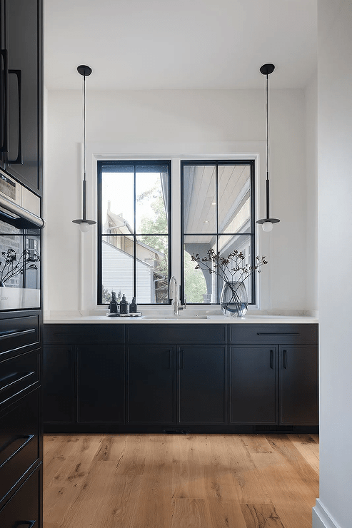 Black and white butler's pantry features black cabinetry with white marble countertop and matte black pulls.