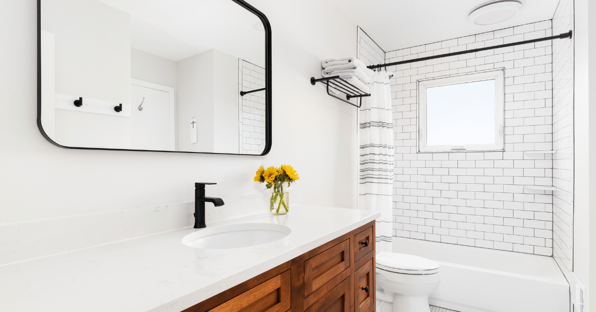 White bathroom with wooden vanity and white subway tile shower.
