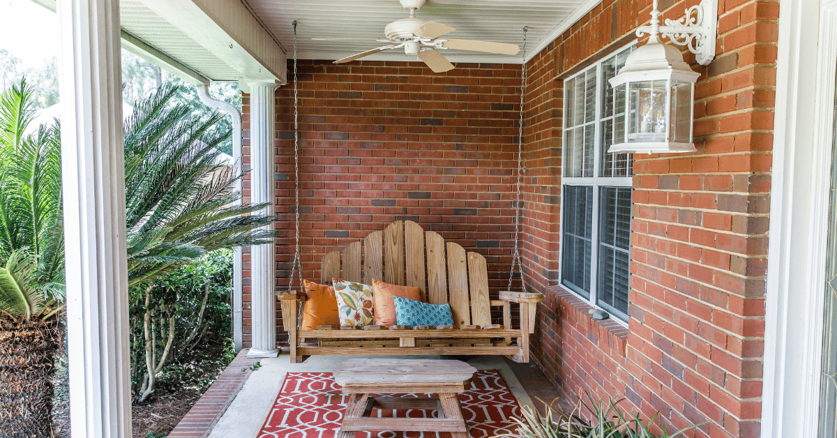 Front porch with swing bench and red rug.