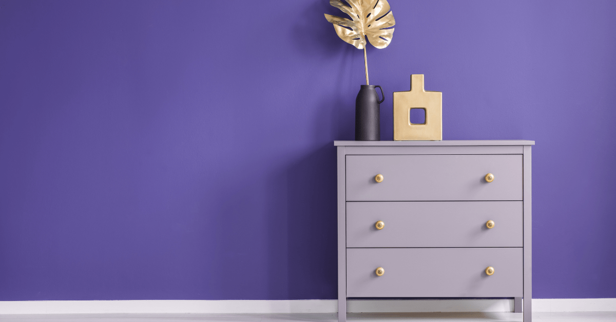 Purple painted dresser flanked by purple wall.
