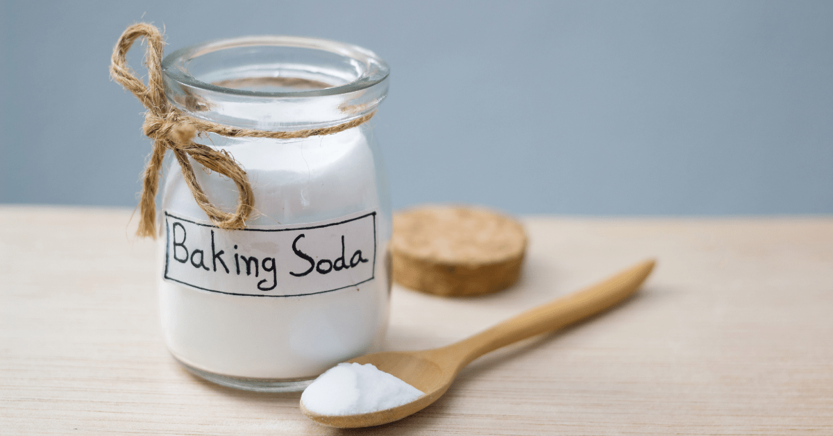 A jar with label that reads "Baking Soda" fronted by a wooden spoon.