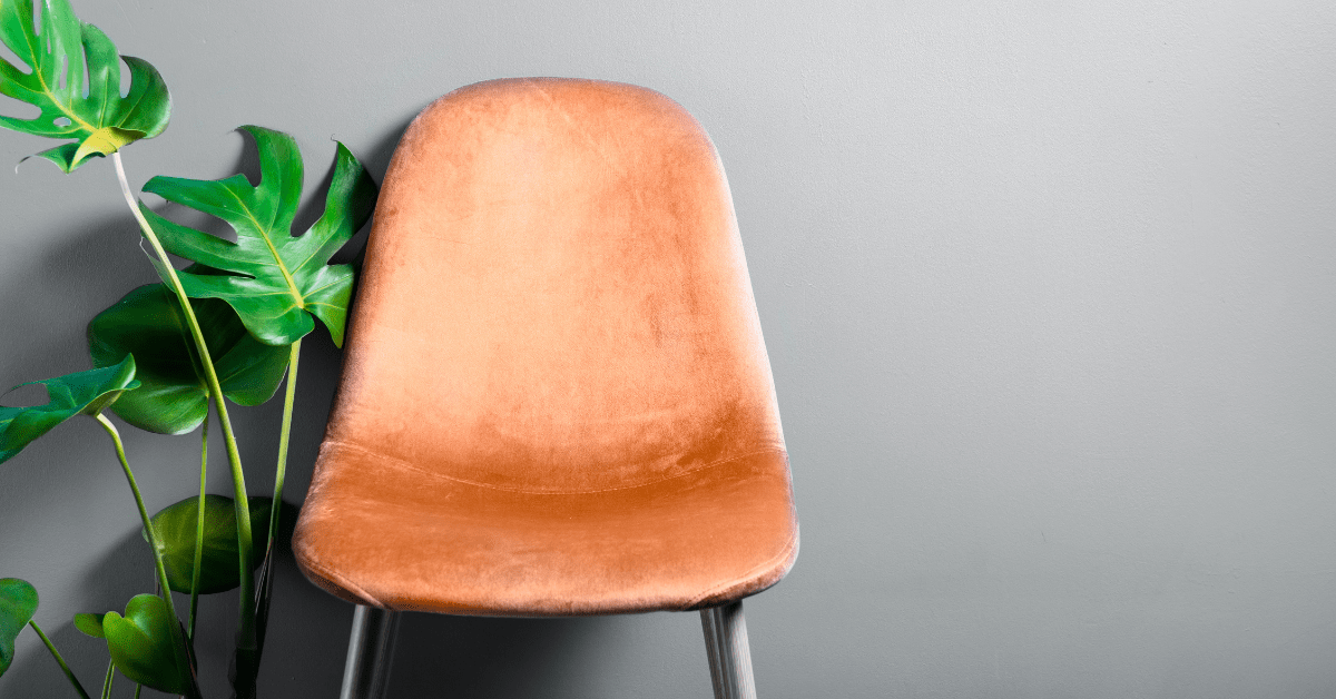 A peach colored chair and plant.