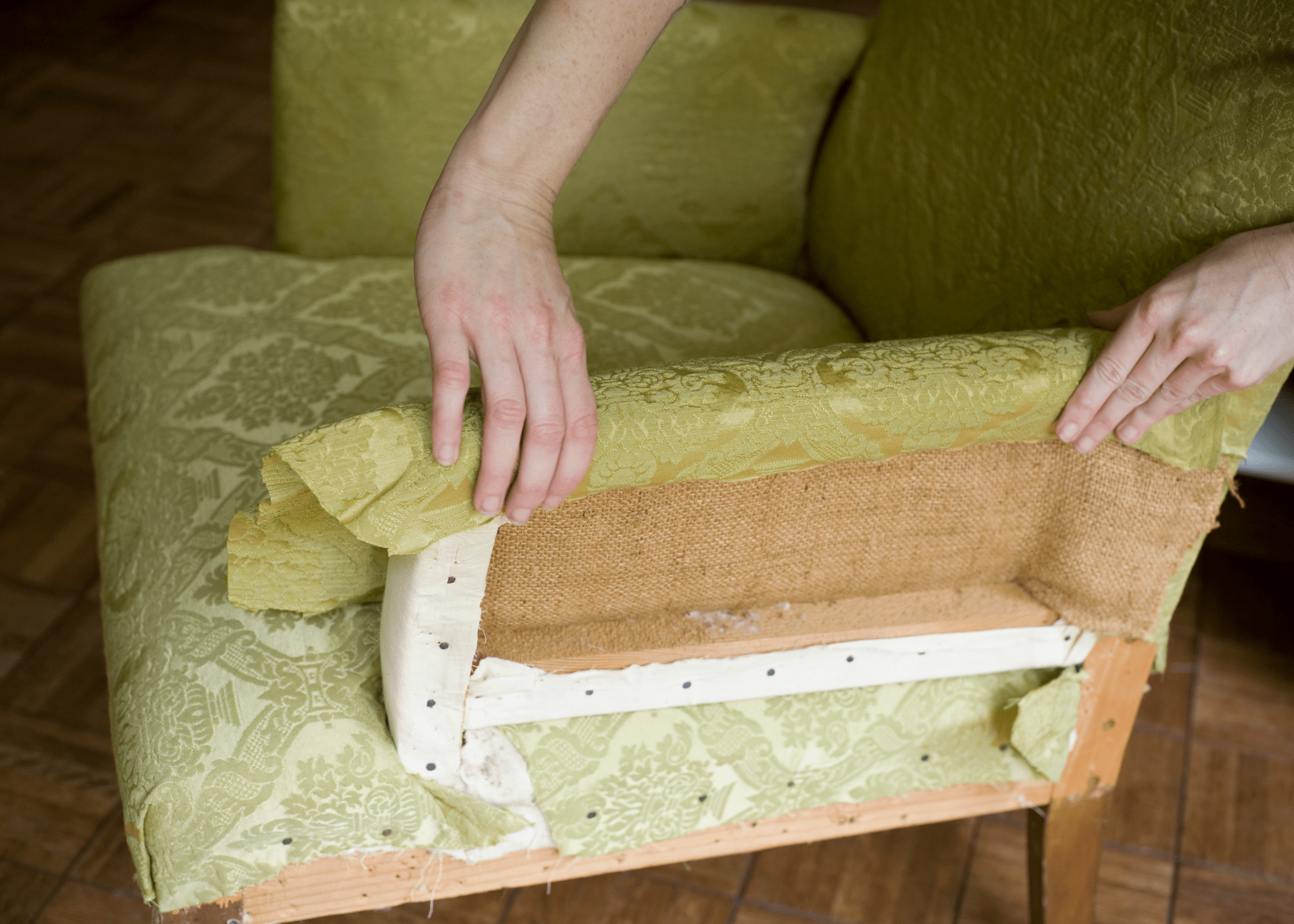 hands repairing a green sitting chair reupholstering furniture