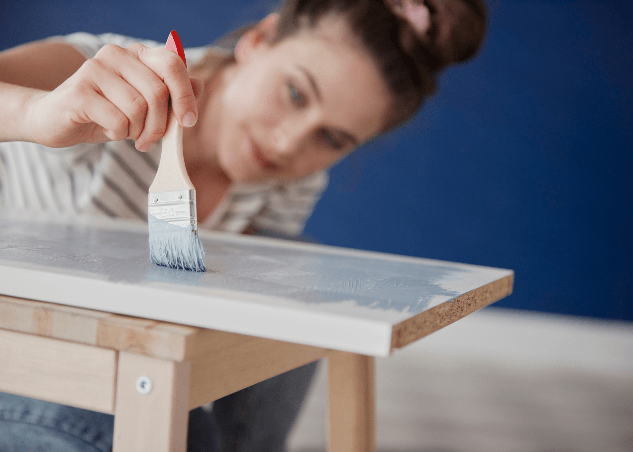 woman painting a piece of mdf blue