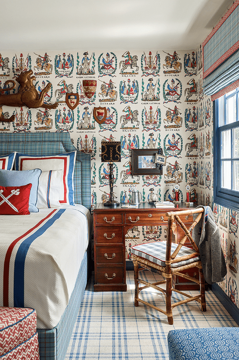 Kid's room features a red and blue plaid bed with red and blue border bedding and a vintage desk as nightstand with a vintage bamboo chair atop blue plaid rug,