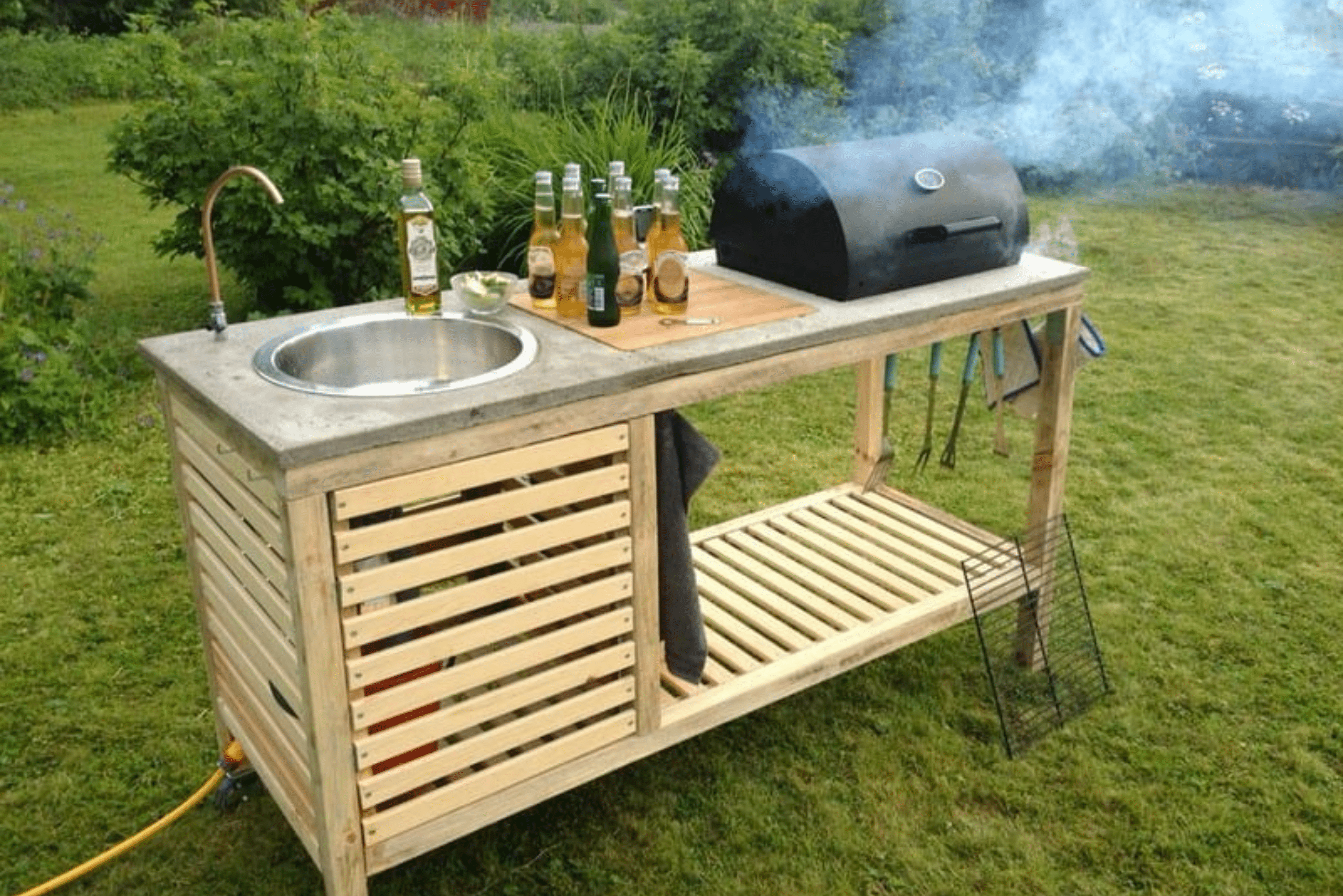A portable grill station made of wood and has a built-in sink and grill.